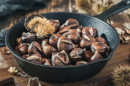 Roasted chestnuts in a cast iron pan on a wooden boardの写真素材