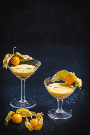 Two glasses with eggnog and physalis fruits on a black background, decorated with silver stars, vertical with copy spaceの写真素材