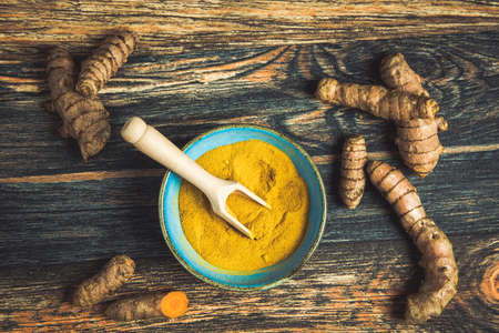 Curcuma powder and roots on a rustic background, top viewの写真素材