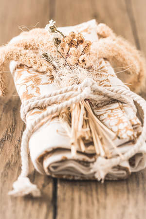 Rolled napkin or tea towel decorated with dried flowers and a ribbon, table decoration in natural colors on a wooden tableの写真素材