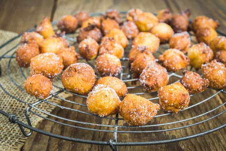 Homemade Castagnole, Mutzen or Castagnole, typical German or italian carnival fritters with sugar on a cooling rackの写真素材