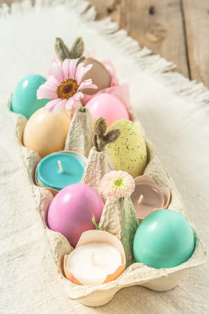Box with pastel-colored easter eggs, candles in eggshells and spring flower blossoms as Easter decorationの写真素材