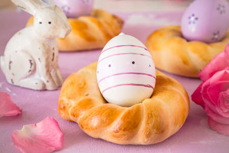 Homemade easter buns with colorful easter eggs on pinkish background