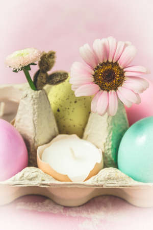 Box with pastel-colored easter eggs, candles in eggshell and spring flower blossoms as Easter decoration, close-up, verticalの写真素材