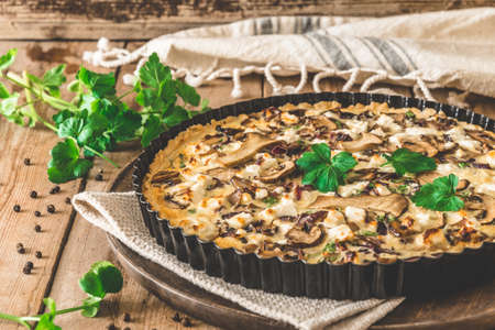 Vegetarian mushroom quiche with parsley on wooden tableの写真素材