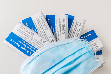 Germany - March 27th 2021: Six Covid-19 rapid antigen tests with german labeling and a protective...