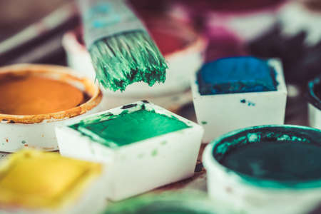 Old paint box with colorful watercolors, brush with green paintの写真素材