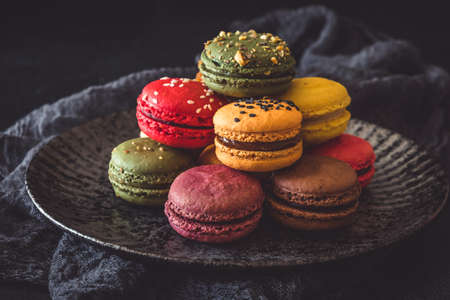 Colorful french macarons on a dark plate on black backgroundの写真素材