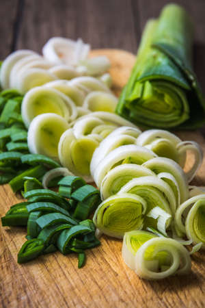 Chopped fresh leek on a wooden board, preparation for cooking, verticalの写真素材