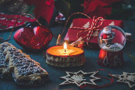 Christmas candle with gingerbread cookies, decorations and poinsettia plant on a dark green backgroundの写真素材