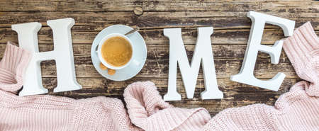 The word home in white letters, the O replaced by a cup of coffee, with a pink wool sweater, concept of cozy atmosphereの写真素材