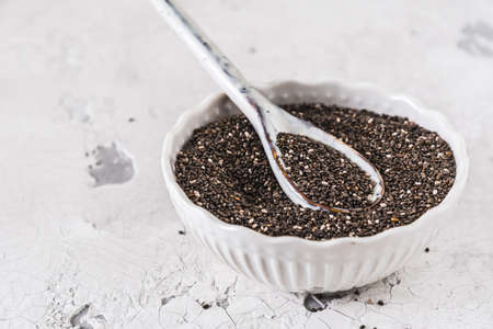 White bowl and spoon with Chia seeds on a white white background, copy spaceの写真素材