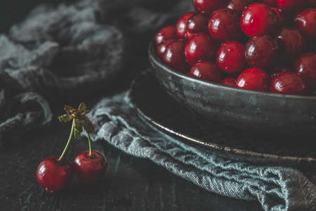 Ripe cherries in a black bowl on black backgroundの写真素材