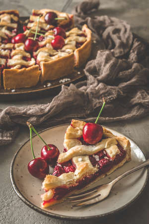 A piece of cherry pie on a plate on gray concrete background, verticalの写真素材