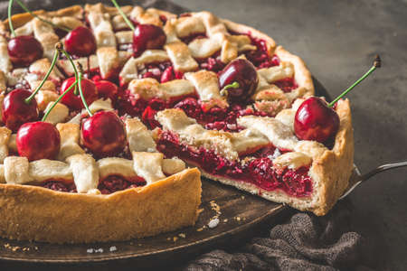 Close up of homemade cherry pie with one piece sticking out