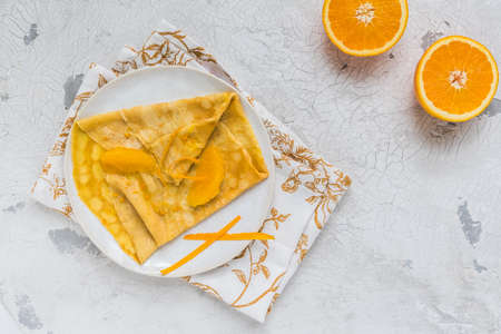 Crepe Suzette, french thin pancake with orange sauce and fruits, white background, top view with copy spaceの写真素材