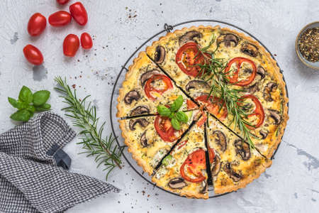 Whole homemade vegetable tart with mushrooms, tomatoes and zucchini on white background, top viewの写真素材