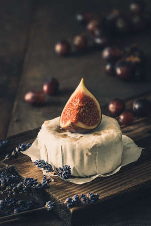 Whole round soft cheese with fig and honey on dark rustic wood, verticalの写真素材