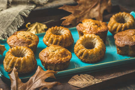 Homemade delicious mini bundt cakes, guglhupf, muffins on a blue plate on rustic wooden background with autumn decorationの写真素材