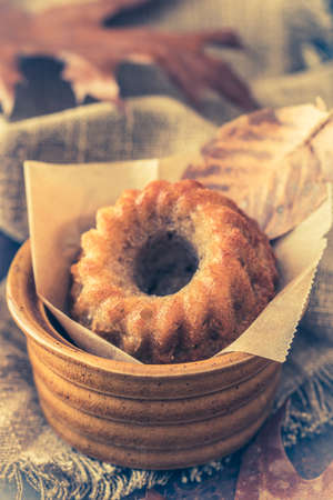 Mini bundt cake, guglhupf, muffin in a rustic bowl with autumn leaves, closeup, verticalの写真素材