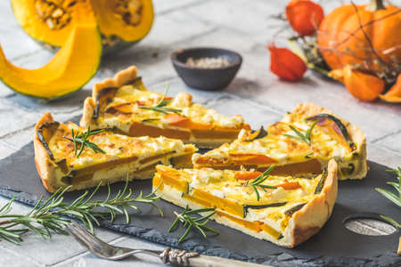 Pieces of pumpkin tart with rosemary on a slate plate on gray backgroundの写真素材