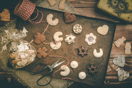 Christmas cookies on a rusty tray on wooden background, scene of preparation for christmas gifts,...