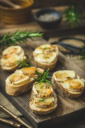 Baguette bread slices baked with goat cheese and honey on wooden background, verticalの写真素材