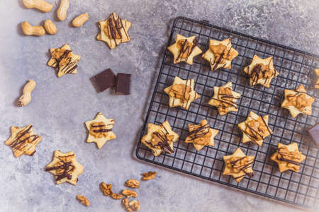 Homemade star shaped cookies with nut caramel topping and chocolate, on a cooling rack and gray background, top viewの写真素材