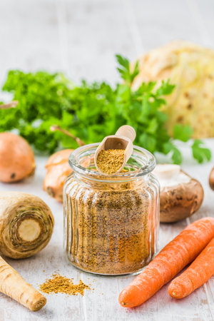 Homemade vegetable broth powder, organic vegetable stock, with raw vegetables on white wooden background, vertical with copy spaceの写真素材