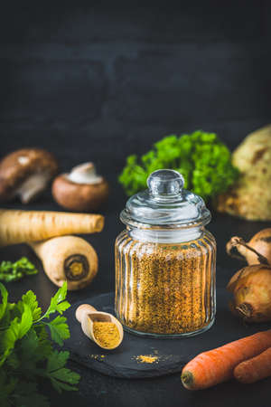 Homemade vegetable broth powder, organic vegetable stock, with raw vegetables on black background, vertical with copy spaceの写真素材