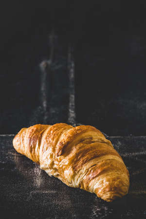 Fresh french croissant on black background, vertical with copy spaceの写真素材