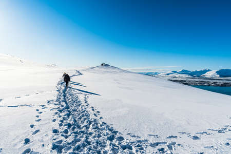 Tourists walking a hiking trail at the top of Storsteinen mountain in Tromso, Norway, on a sunny winter dayの写真素材