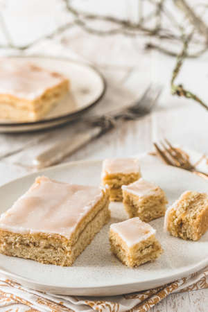 Pieces of covered apple pie with sugar icing on a white wooden background. Harmonious color concept in beige tones. vertical.の写真素材