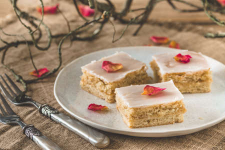 Pieces of covered apple pie with sugar icing and rose leaves on a rustic wooden background, decorated with branchesの写真素材