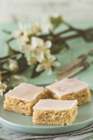 Pieces of covered apple pie with sugar icing on a light green background, decorated with flowering...