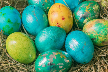 Metallic shimmering buten Easter eggs in blue green colors on straw, close-upの写真素材