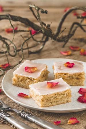 Pieces of covered apple pie with sugar icing and rose leaves on a rustic wooden background, decorated with branches, verticalの写真素材