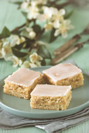 Pieces of covered apple pie with sugar icing on a light green background, decorated with flowering branch, verticalの写真素材