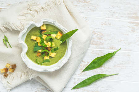 Wild garlic soup with croutons on a white wooden table, top view with copy spaceの写真素材