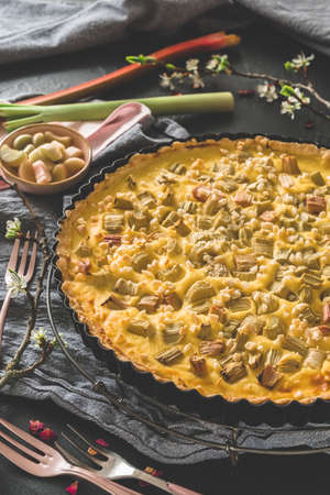 Whole homemade rhubarb tart on a dark table, verticalの写真素材