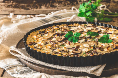 Vegetarian mushroom tart with parsley on a wooden tableの写真素材