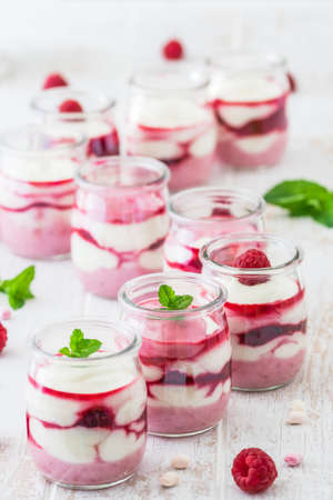 Fruity quark dessert with raspberries in small glasses and chocolate or crisp topping in a row, verticalの写真素材