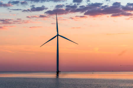 Wind turbine in the sea in the warm sunset lightの写真素材