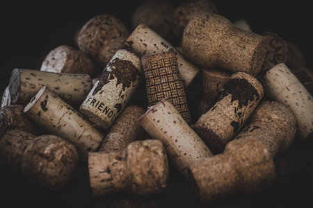 Two corks on a pile of used corks which show a world map and the word friendly. Dark background. Concept of a better world.の写真素材