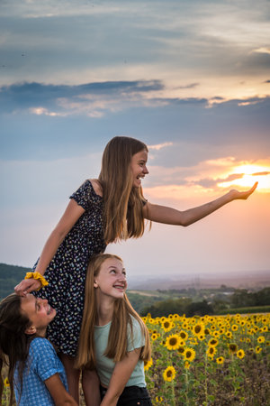 Three girls have fun in the setting sun, vertical with copy spaceの写真素材