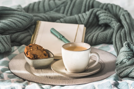 Cup of coffee and cookies on cozy bed. Warm wool sweater for a cozy autumn weekend, breakfast in bed, coffee break. Hygge concept.の写真素材