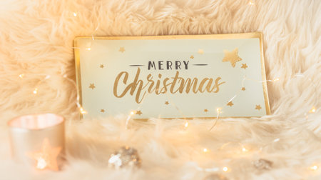 Merry Christmas lettering on a glass sign or tray on a white fur along with Christmas decorations and lightsの写真素材