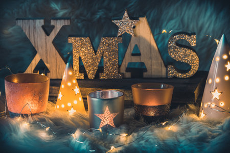 Word xmas in wooden capital letters, upper case, and different christmas candle lights and fairy lights on a furの写真素材