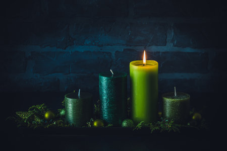 Advent wreath with four different candles in green colors on dark background, christmas decoration, copy spaceの写真素材