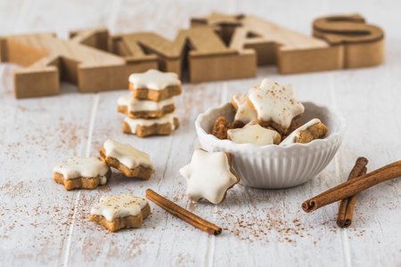 Christmas cinnamon star biscuits on a white wooden table, in the background wooden letters xmasの写真素材